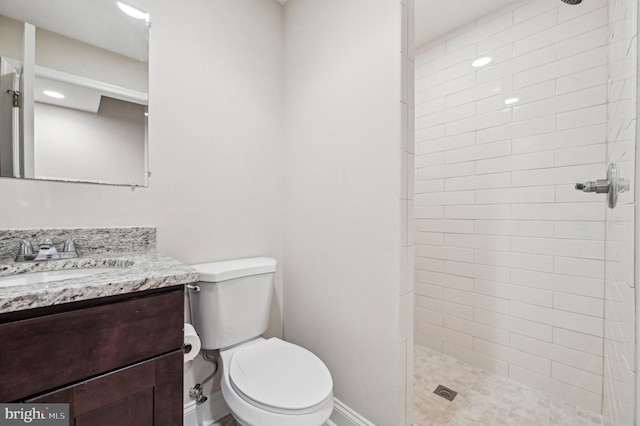 bathroom with vanity, toilet, and a tile shower