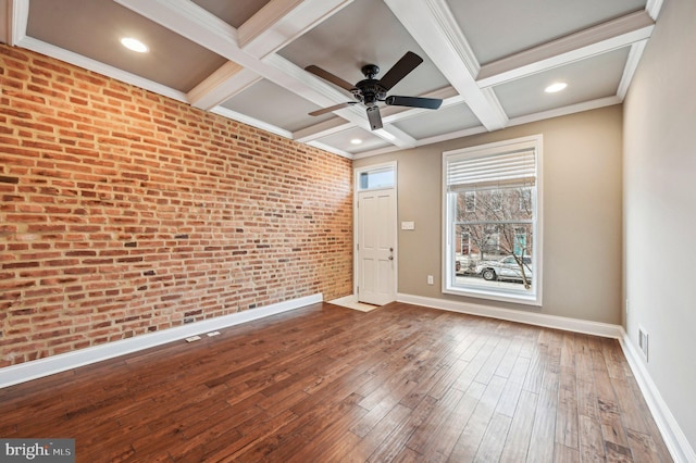 empty room with hardwood / wood-style flooring, brick wall, coffered ceiling, and beam ceiling