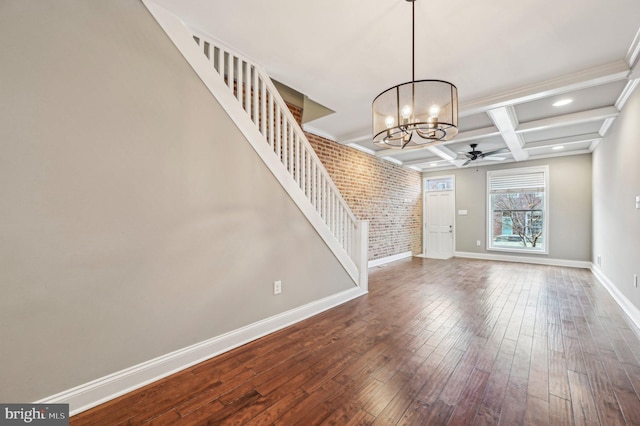 interior space featuring brick wall, ceiling fan with notable chandelier, beamed ceiling, hardwood / wood-style flooring, and coffered ceiling