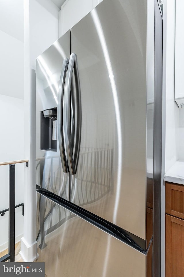 room details featuring stainless steel fridge with ice dispenser and white cabinets