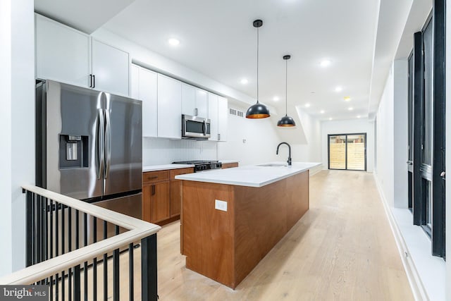 kitchen featuring stainless steel appliances, white cabinetry, sink, and an island with sink