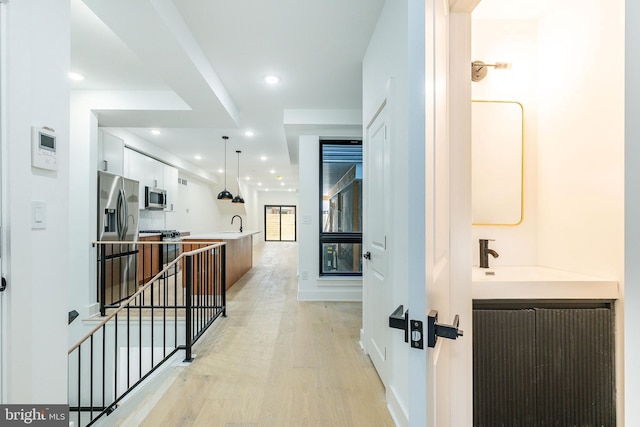 corridor featuring sink and light hardwood / wood-style flooring