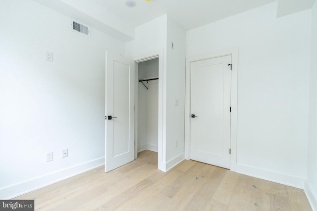 unfurnished bedroom with a closet and light wood-type flooring