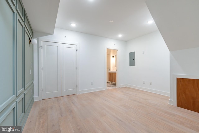 unfurnished bedroom featuring ensuite bath, electric panel, and light wood-type flooring