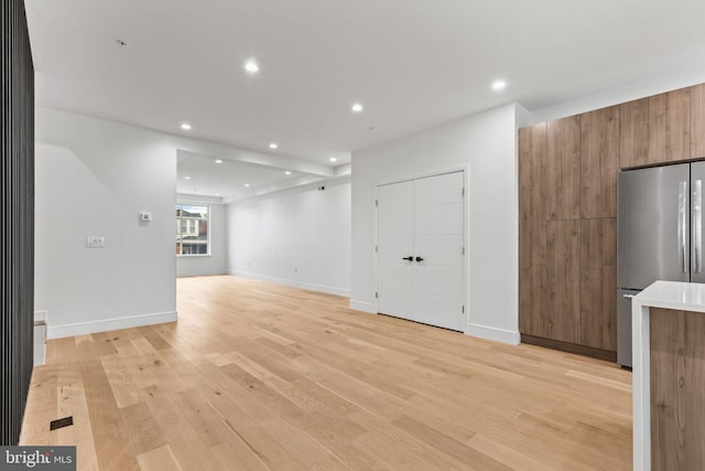 unfurnished living room with recessed lighting, light wood-style floors, and baseboards