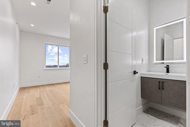 bathroom featuring recessed lighting, vanity, baseboards, and wood finished floors