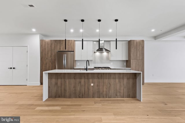 kitchen with modern cabinets, freestanding refrigerator, white cabinets, wall chimney exhaust hood, and light countertops