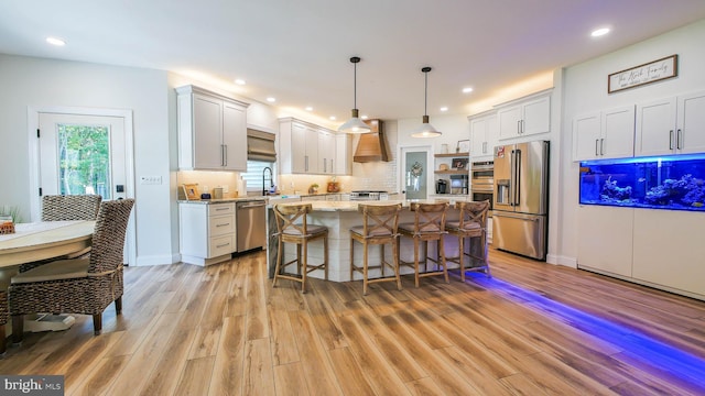 kitchen featuring a kitchen island, appliances with stainless steel finishes, pendant lighting, white cabinets, and light stone countertops