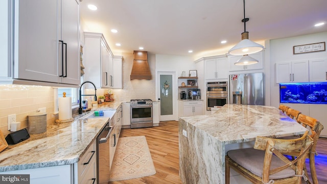 kitchen with pendant lighting, white cabinetry, sink, custom exhaust hood, and stainless steel appliances