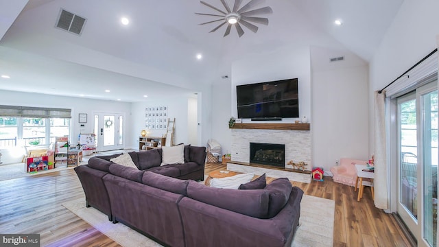 living room with a fireplace, wood-type flooring, and high vaulted ceiling