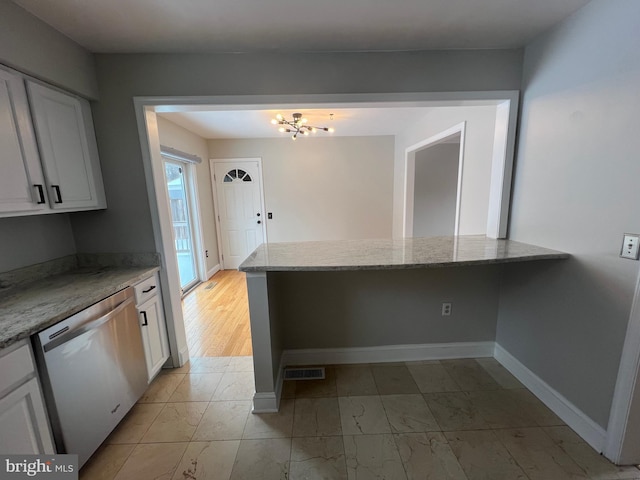 kitchen with built in desk, dishwasher, kitchen peninsula, light stone countertops, and white cabinets