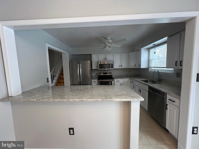 kitchen with sink, kitchen peninsula, ceiling fan, stainless steel appliances, and light stone countertops