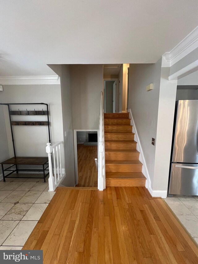 stairs with hardwood / wood-style flooring and ornamental molding