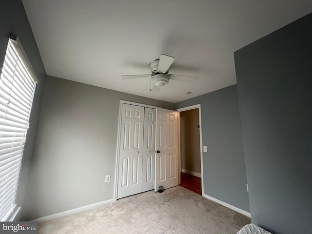 unfurnished bedroom featuring light colored carpet, a closet, and ceiling fan