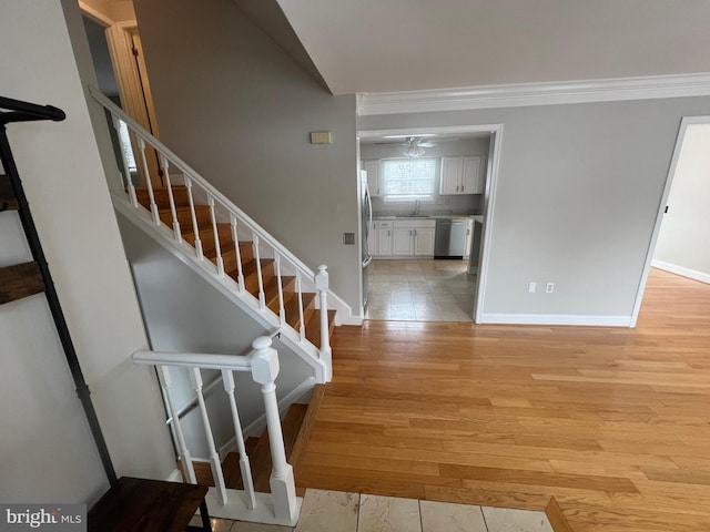 stairway with wood-type flooring, sink, and crown molding