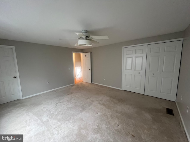 unfurnished bedroom with light colored carpet, a closet, and ceiling fan