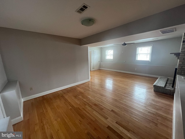 interior space featuring ceiling fan, light hardwood / wood-style floors, and a brick fireplace