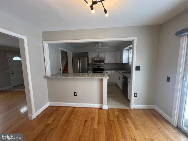 kitchen featuring sink, light wood-type flooring, appliances with stainless steel finishes, kitchen peninsula, and white cabinets