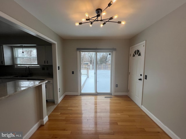 unfurnished dining area featuring a chandelier, light hardwood / wood-style floors, and sink