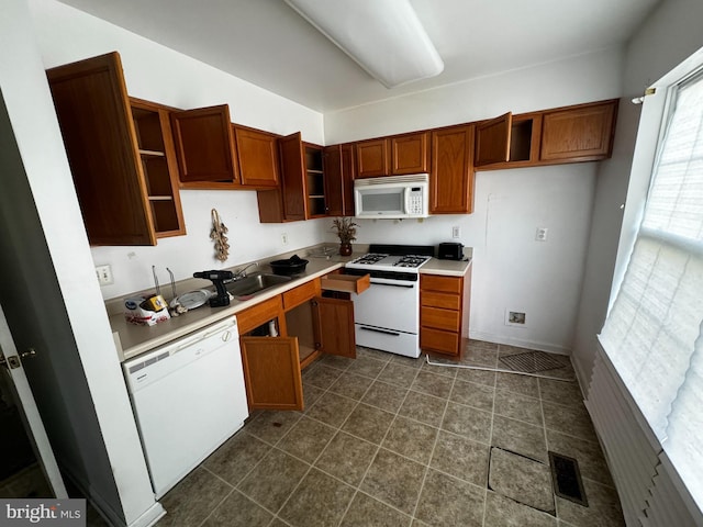 kitchen with dark tile patterned floors, sink, and white appliances