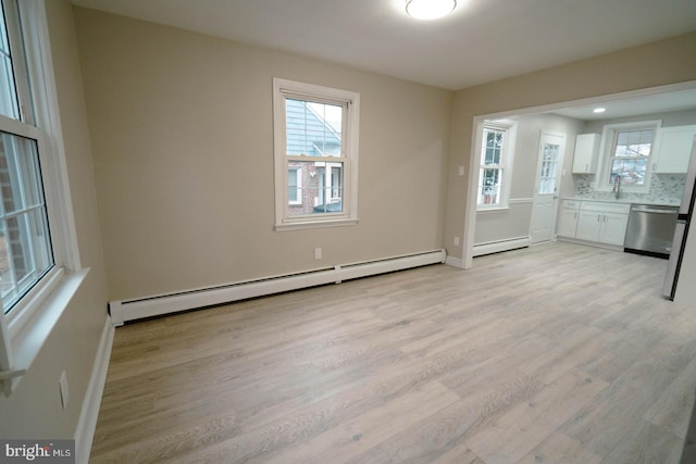 unfurnished dining area featuring baseboard heating, sink, and light hardwood / wood-style flooring