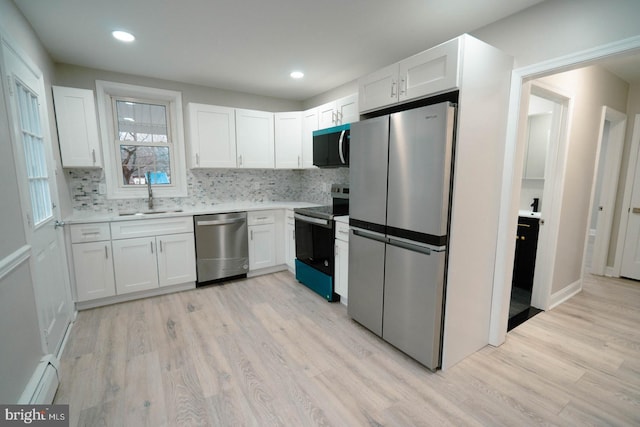 kitchen featuring sink, white cabinetry, a baseboard heating unit, stainless steel appliances, and light hardwood / wood-style floors