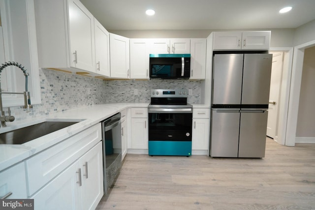 kitchen featuring sink, white cabinetry, light stone counters, light hardwood / wood-style flooring, and stainless steel appliances