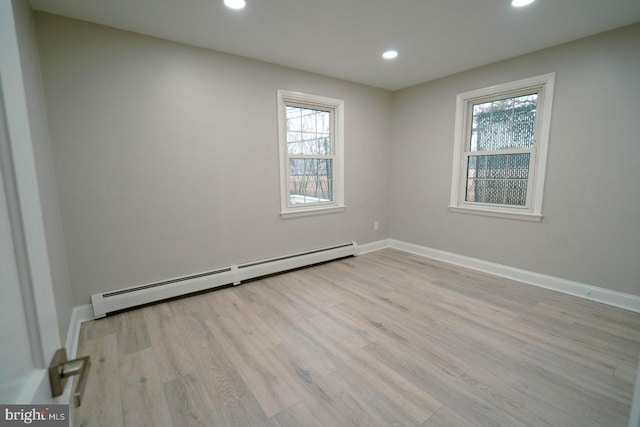 spare room featuring a baseboard heating unit and light hardwood / wood-style flooring