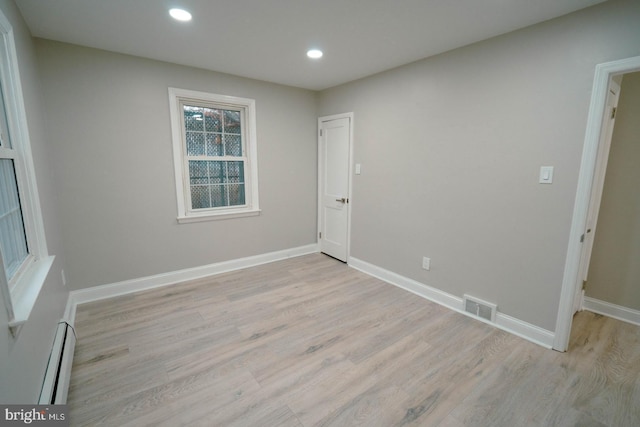 empty room featuring a baseboard radiator and light hardwood / wood-style floors