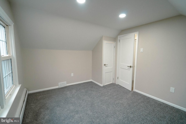 additional living space featuring vaulted ceiling, a baseboard radiator, and dark colored carpet