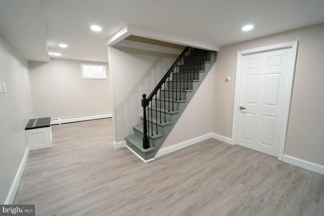 basement with a baseboard heating unit and light wood-type flooring