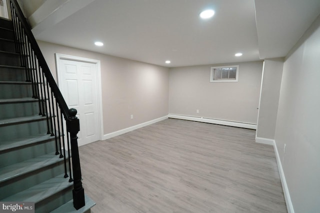 basement featuring light wood-type flooring and baseboard heating