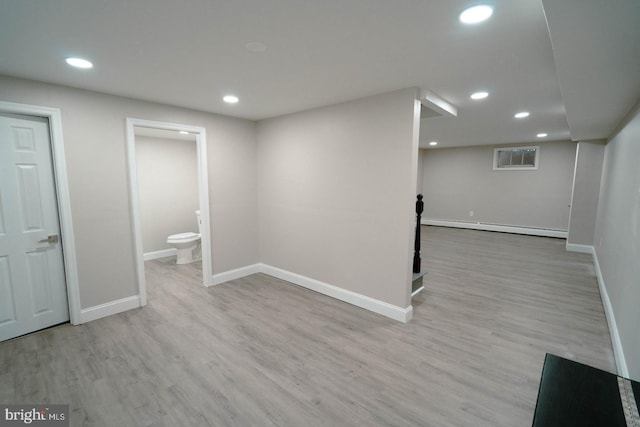 basement with light wood-type flooring and baseboard heating