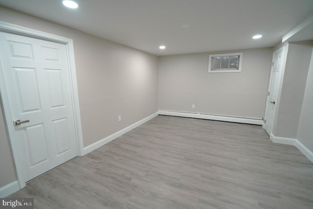 basement featuring a baseboard radiator and light wood-type flooring