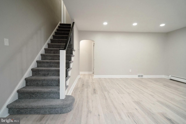 stairs featuring a baseboard radiator and hardwood / wood-style floors