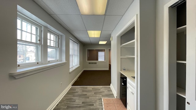 hall featuring wine cooler, hardwood / wood-style flooring, and a drop ceiling