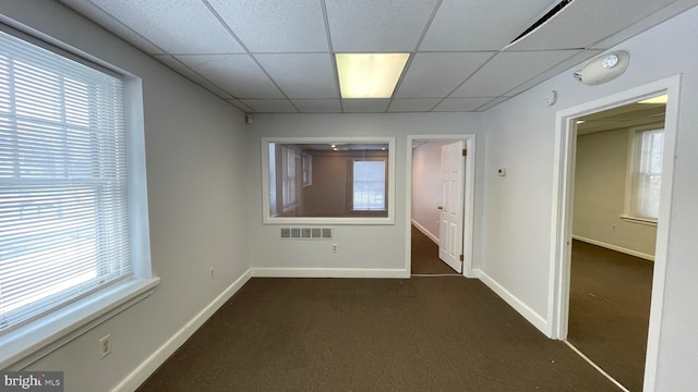 carpeted empty room featuring a paneled ceiling