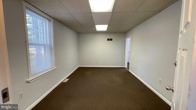 carpeted spare room featuring a drop ceiling