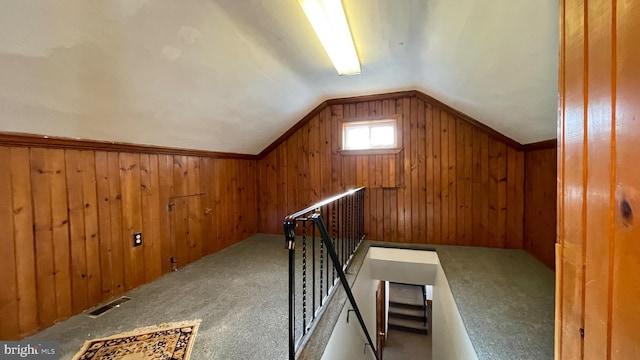 bonus room with lofted ceiling, wooden walls, and carpet