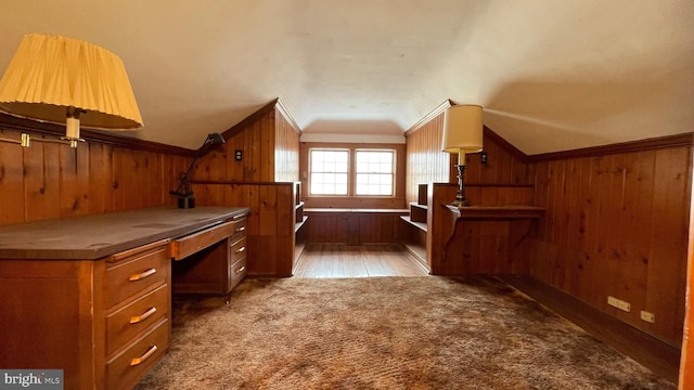 bonus room featuring dark carpet, wooden walls, and vaulted ceiling