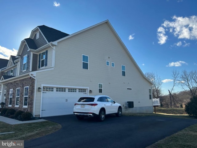 view of home's exterior featuring a garage, stone siding, and aphalt driveway