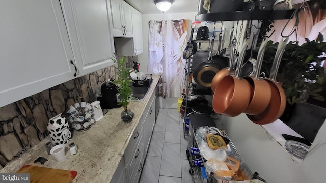 kitchen with light stone countertops, white cabinets, and light tile patterned flooring