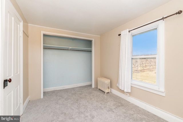 unfurnished bedroom featuring radiator, light carpet, and a closet