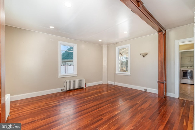 spare room featuring dark hardwood / wood-style floors, washer / clothes dryer, and radiator