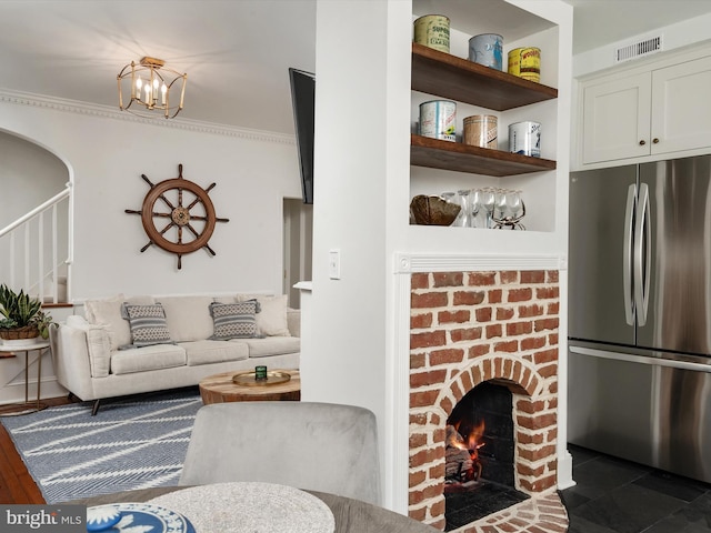 143 Market St, Annapolis, MD 21401 - living room featuring crown molding, a brick fireplace, and a notable chandelier