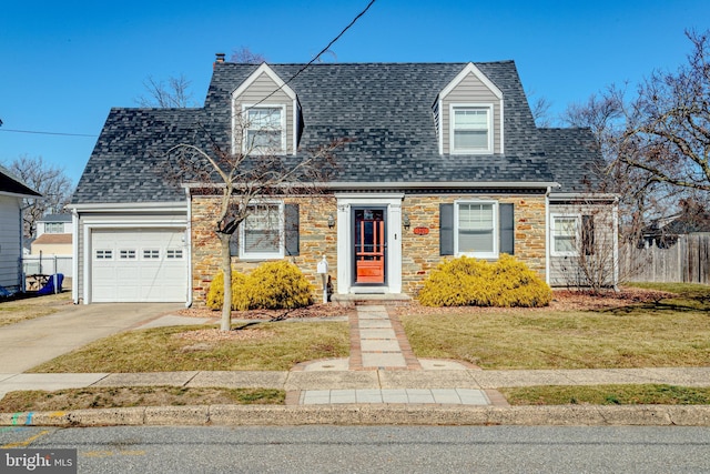 cape cod home with roof with shingles, concrete driveway, an attached garage, fence, and stone siding