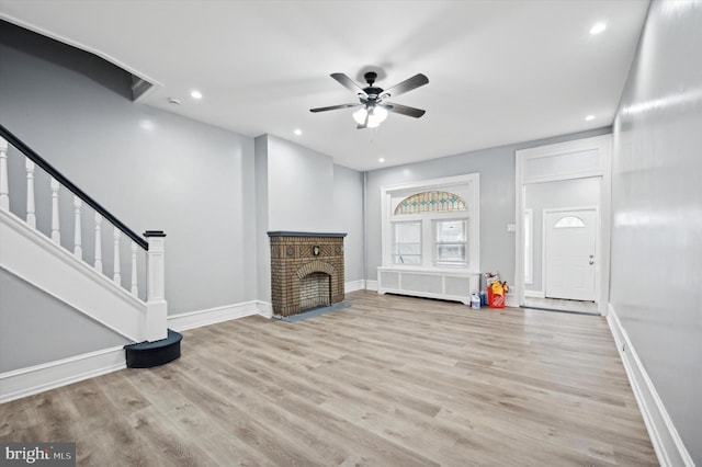 unfurnished living room with ceiling fan, radiator heating unit, a fireplace, and light hardwood / wood-style flooring