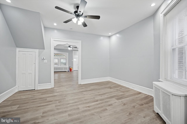 empty room with ceiling fan, radiator heating unit, and light wood-type flooring