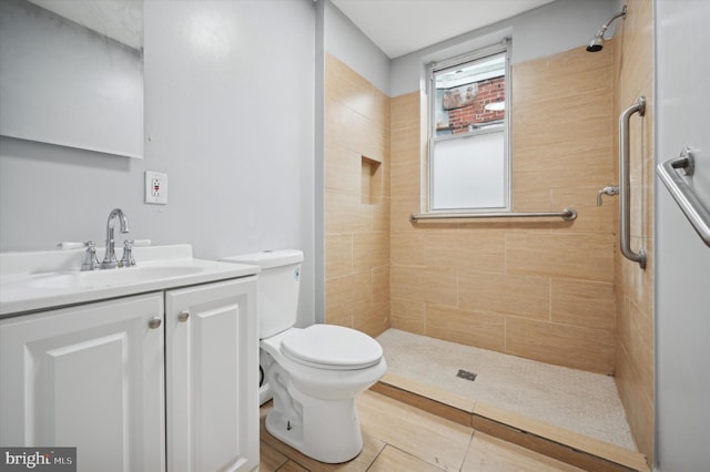 bathroom with a tile shower, vanity, and toilet