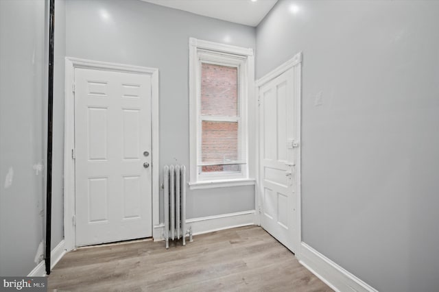 foyer entrance with radiator heating unit and light hardwood / wood-style floors